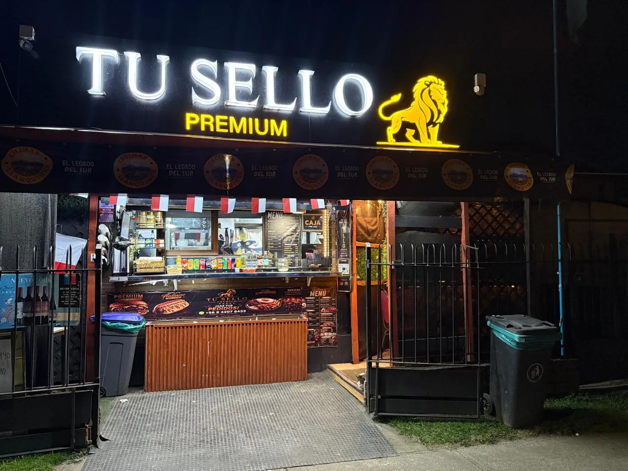 Fachada nocturna de Tú Sello Premium en Av. René Soriano 2121, con el letrero y el león iluminados