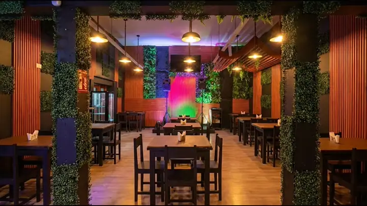 Salón de Tú Sello Premium con sus paredes de madera, muros verdes y el escenario iluminado al fondo